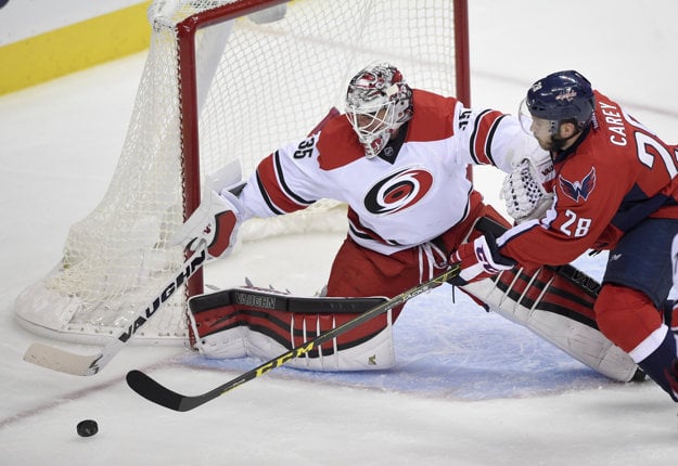 Hráč Washingtonu Capitals Paul Carey (vpravo) sa dostáva do šance pred brankárom Caroliny Hurricanes Alexom Nedeljkovicom.