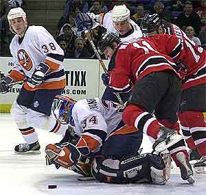 john madden z new jersey devils padá na brankára new yorku islanders johna vanbiesbroucka, ktorý sa snaží chytiť puk v zápase hokejovej nhl v uniondale, 31.1.2001. celú akciu sleduje dave scatchard (38) z n.y. lslanders. tasr