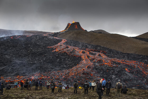Ľudia sledujú vytekajúcu lávu počas erupcie sopky na polostrove Reykjanes na juhozápade Islandu.