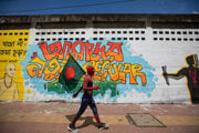 Protestujúci v kostýme Spidermana prechádza popred grafiti s významom: Náš nový sekulárny Bangladéš.