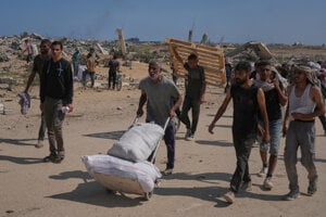 Palestínčania nesú balíčky s humanitárnou pomocou v blízkosti distribučného centra Nadácie pre humanitárnu pomoc v Gaze.