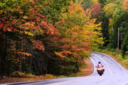 Motocyklista jazdí okolo stromov s mieniacimi farbami počas jesene v meste New London, v americkom štáte New Hampshire.