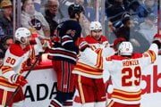 Blake Coleman, Mikael Backlund a Samuel Honzek oslavujú gól.