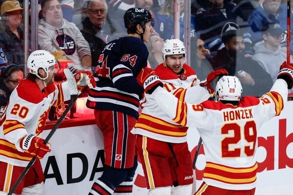 Blake Coleman, Mikael Backlund a Samuel Honzek oslavujú gól.
