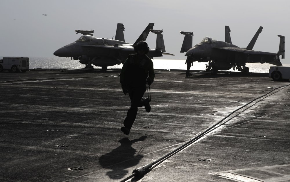Člen palubného personálu americkej lietadlovej lode USS Dwight D. Eisenhower beží po palube počas prípravy lietadiel  F-18 Super Hornet. FOTO - TASR/AP