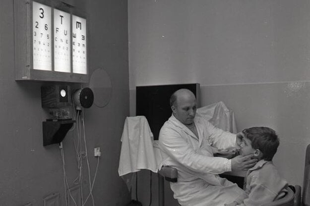Jozef Javorský meria cez priz-mu uhol škúlenia dieťaťa pomocou zvukovo-svetelného fixačného prístroja.