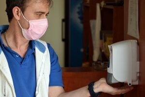 Čašník s ochranným rúškom si dezinfikuje ruky počas provizórneho výdaja balených obedov v súvislosti s opatreniami proti šíreniu koronavírusu v reštaurácii v Trebišove.