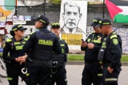 Polícia stojí pred transparentom s nápisom v španielčine „Uribe je vinný“, ktorý vyvesili odporcovia bývalého prezidenta Álvara Uribeho pred súdom.
