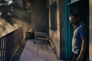 Muž sa 25. júla prechádza po balkóne Národnej nemocnice v Sweide, zatiaľ čo zdravotnícky personál čistí priestory vodnými pumpami.
