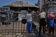 Palestínske deti čakajú v komunitnej kuchyni, kým sa v Gaze pripraví a rozdá jedlo.