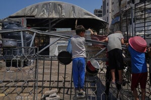 Palestínske deti čakajú v komunitnej kuchyni, kým sa v Gaze pripraví a rozdá jedlo.