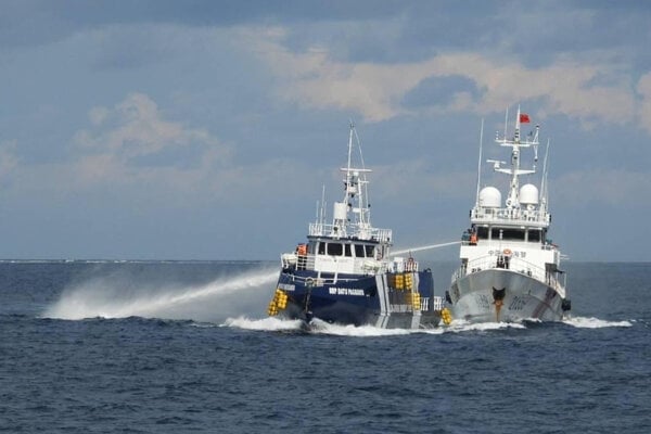 Plavidlo čínskej pobrežnej stráže (vpravo) strieľa z vodného dela na filipínsku pobrežnú loď BRP Datu Pagbuaya.