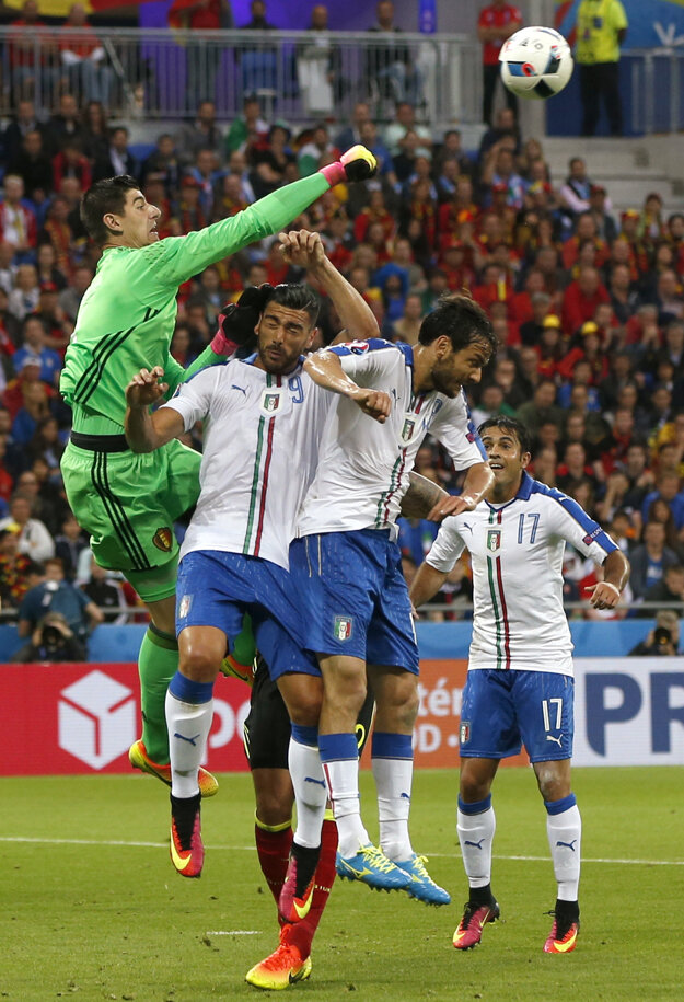 Brankár Chelsea Thibaut Courtois boxuje loptu pred trojicou Talianov.