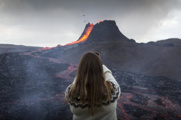 Žena si fotí vytekajúcu lávu počas erupcie sopky na polostrove Reykjanes na juhozápade Islandu.