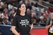 Caitlin Clarková v tričku „Zaplaťte nám, čo nám patrí“.