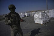 Izraelský vojak stojí vedľa balíkov s humanitárnou pomocou, ktoré čakajú na vyzdvihnutie na palestínskej strane hraničného priechodu Kerem Šalom v Pásme Gazy vo štvrtok 24. júla 2025 počas mediálnej prehliadky organizovanej izraelskou armádou.