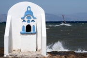 Windsurfista skáče cez vlnu počas veterného dňa v Aténach.