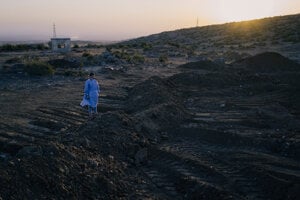 Zdravotnícky pracovník stojí pri masovom hrobe v al-Raha, na južnom okraji Sweidy, 25. júla.