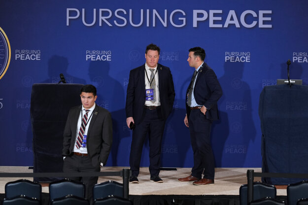 Zamestnanci Bieleho domu stojí na pódiu, kde sa uskutoční tlačová konferencia.