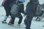 Turisti v teniskách v zasneženom horskom teréne.