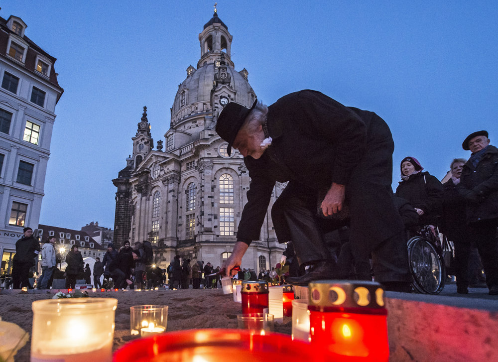 Muž zapaľuje sviečku na námestí pred chrámom Frauenkirche v nemeckých Drážďanoch.