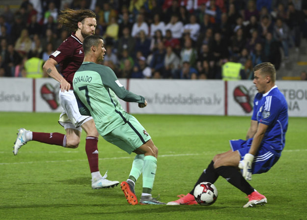 Cristiano Ronaldo zakončuje v šanci pred brankárom Andrisom Vaninsom.