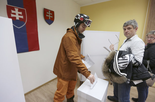 Volič vhadzuje obálku do urny vo volebnej miestnosti v Demänovskej Doline.