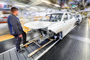 Na archívnej snímke zo 7. marca 2025 zamestnanec stojí pri aute nemeckej automobilky Volkswagen v závode vo Wolfsburgu.
