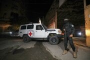  Ozbrojený militant z Brigády Izzadín al-Kassám, vojenskej odnože Hamasu, stráži vozidlá Červeného kríža, ktoré vchádzajú do skladu v meste Gaza, kde majú údajne vyzdvihnúť rakvy s telami štyroch mŕtvych rukojemníkov v utorok 14. októbra. 
