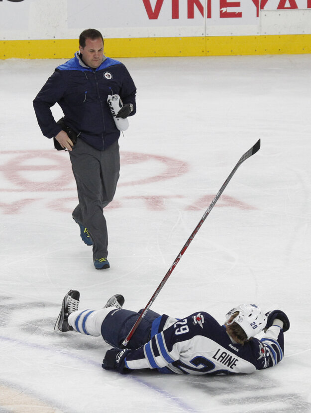 Patrik Laine leží na ľade po zákroku súpera.