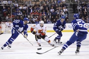 Nazem Kadri (vľavo) a Martin Marinčin (vpravo) z Toronta zdvojujú útočníka Calgary Johnnyho Gaudreaua.