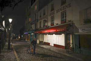 Muž tlačí bicykel v parížskej štvrti Montmartre.
