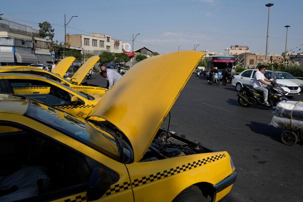 Taxikári otvárajú kapoty svojich áut, zatiaľ čo čakajú na cestujúcich počas horúceho letného dňa na námestí v centre Teheránu.