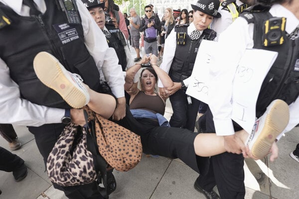 Policajti odvádzajú ženu zatknutú na proteste.