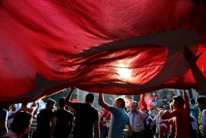 Ľudia držia tureckú vlajku počas protestu proti pokusu o prevrat v krajine.