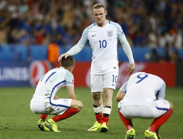 Wayne Rooney (v strede) utešuje spoluhráčov po prehre s Islandom.
