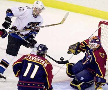 peter bondra (12) z washingtonu capitals sa snaží dostať puk za chrbát brankára atlanty thrashers damiana rhodesa (1) v zápase hokejovej nhl vo washingtone, 1.1.2001. v popredí dean sylvester z thrashers. tasr