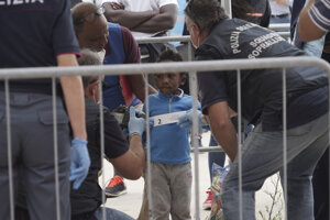 Policajti fotografujú 4-ročného chlapca, migranta z Kamerunu po jeho vylodení z humanitárnej lode Ocean Viking.