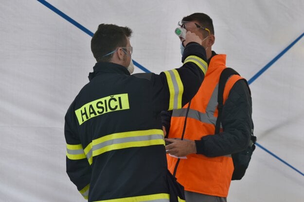Hasič meria teplotu zamestnancovi koncernu Groupe PSA v Trnave
