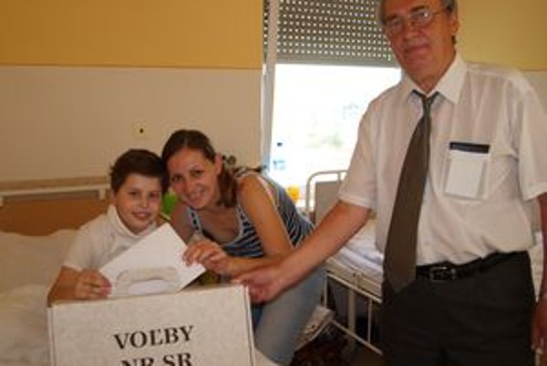 V nemocnici v Nitre volila aj Elena Gažiková so synom Tomášom. Vpravo člen okrskovej volebnej komisie Gejza Rácz.