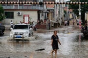 Na snímke žena kráča po zaplavenej ceste po silných dažďoch v štvrti Mi-jün na predmestí Pekingu 