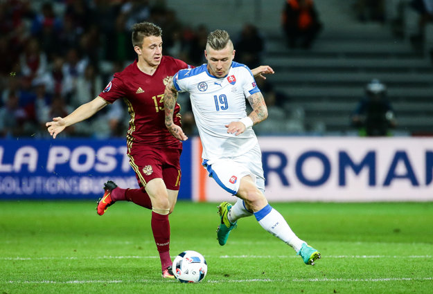 Juraj Kucka (vpravo) sa v zápase s Ruskom pokúša s loptou obísť Aleksandra Golovina.