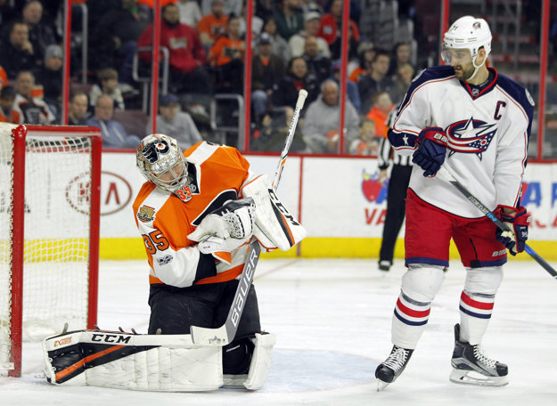 Brankár Philadelphie Steve Mason (vľavo) zasahuje pred cloniacim Nickom Folignom.