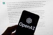 Logo OpenAI sa zobrazuje na mobilnom telefóne pred obrazovkou počítača zobrazujúcou výstup z ChatGPT.