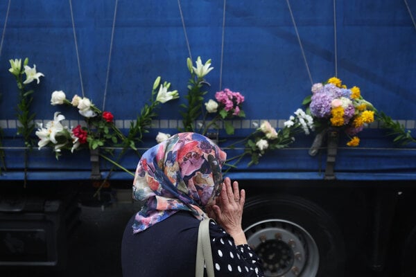 Žena sa modlí , keď nákladné auto priváža pozostatky identifikovaných obetí srebrenickej masakry na cintorín v obci Potočari neďaleko Srebrenice v Bosne.