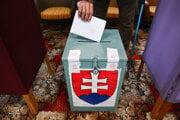 Volič a volebná urna počas doplňujúcich komunálnych volieb.