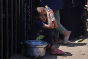 Palestínsky chlapec sedí na zemi a čaká pri výdajni potravín v Chán Júnise.