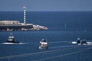 Aktivisti v oranžových vestách sedia na palube lode flotily Sumud smerujúcej do Gazy, zatiaľ čo izraelskí námorní vojaci s ňou vplávajú do prístavu v Izraeli.