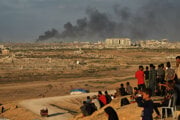 Vysídlení Palestínčania sledujú, ako stúpa dym po útokoch izraelskej armády, keď sa zhromažďujú na pobrežnej ceste v Pásme Gazy.