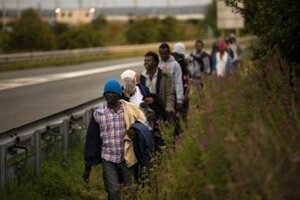Migranti kráčajú pri ceste k tunelu pod Lamanšským prielivom vo francúzskom Calais.